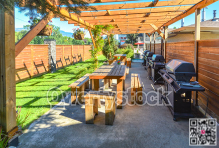 Barbecue and picnic area of hotel with row of tables and grills under the shed.