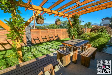 Barbecue and picnic area of hotel with row of tables and grills under the shed.