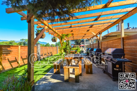 Barbecue and picnic area of hotel with row of tables and grills under the shed.
