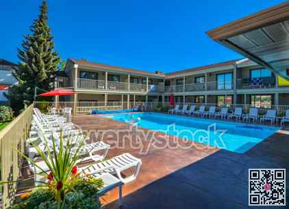 A hotel swimming pool with chaise-longues on side.