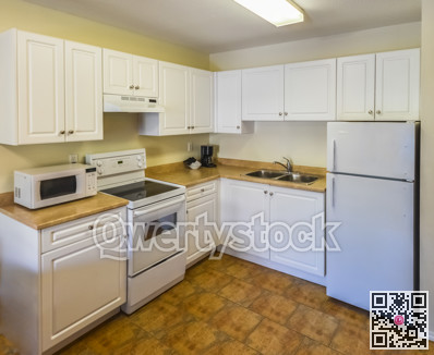 Conventional white kitchen with the table and chairs in dinner area.