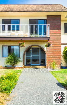 Main entrance of residential house with concrete pathway in front on sunny day.
