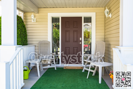 Family house main entrance with blossoming flowers and chairs under the porch