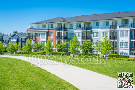 Concrete pathway across green lawn in front of residential condo building
