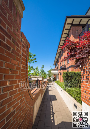 Paved ramp to the entrance of new apartment building on sunny day with blue sky.