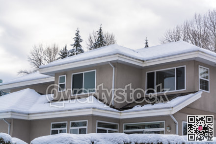 Top of residential house in snow on winter cloudy day.