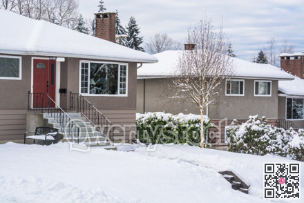 Street of family houses and front yards in snow on winter cloudy day