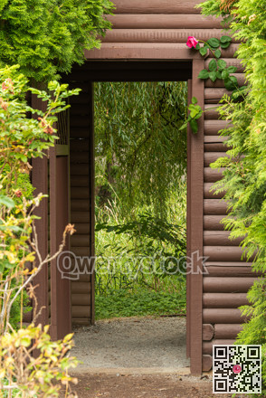 Log crafted gate with red rose above the entrance.