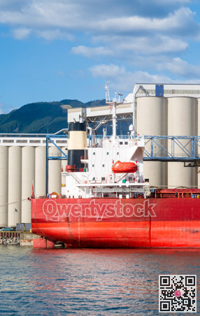 Aft end of dry-cargo ship moored at marine terminal for loading.