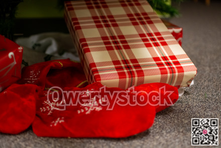 Christmas gifts laying on the floor under fir tree branches.