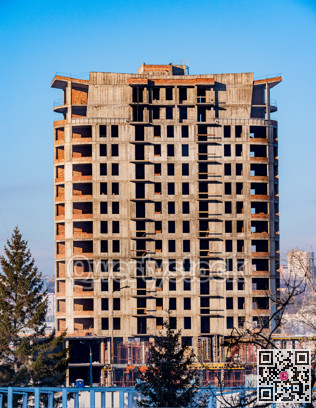 Concrete high-rise building under construction on blue sky background.