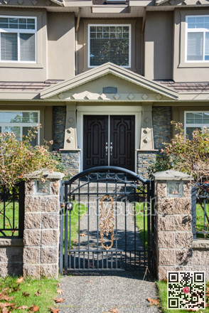 Entrance of luxury residential house with big front yard behind the grid fence