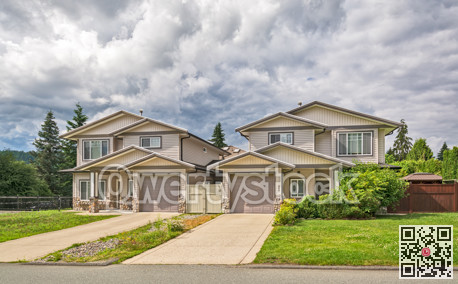 Residential duplex building with concrete driveway and green lawn in front