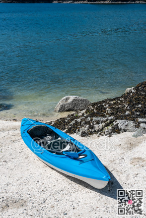 Blue lightweight canoe boat on a shore of ocean bay on sunny day