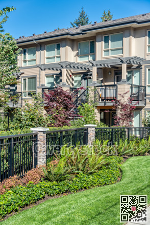 Fresh lawn in front residential townhouse building on blue sky background