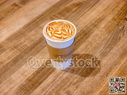 Medium cap of caramel cappuccino on wooden table texture