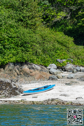 Blue lightweight canoe boat on a shore of ocean bay on sunny day