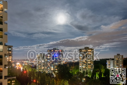 Night cityscape with full moon in clouds