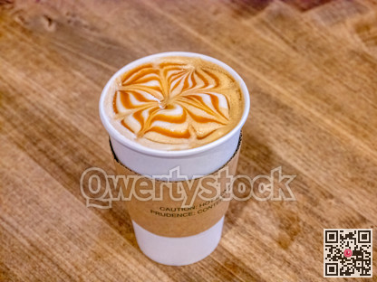 Medium cap of caramel cappuccino on wooden table texture