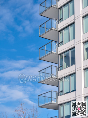 Corner of residential high rise building on blue cloudy sky background