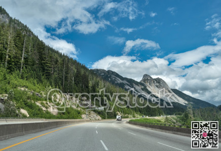 Slow curve on the Coquihalla highway with massive rocky mountain view