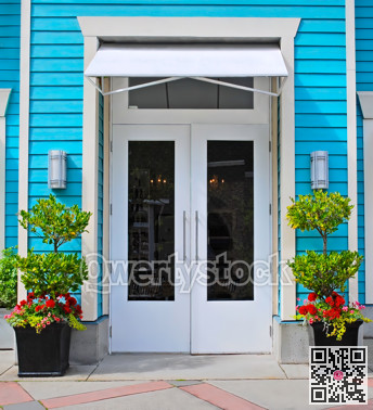 A shop entrance with decorative flowers at the doors