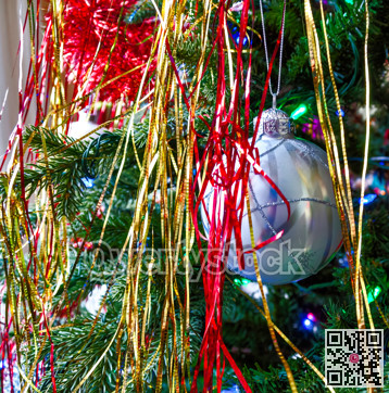 Silver bauble with silver straps on chistmas tree among decorations