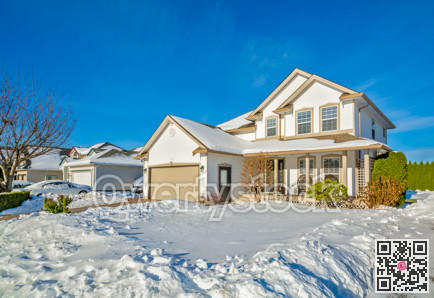 Family house with driveway and front yard in snow on winter sunny day