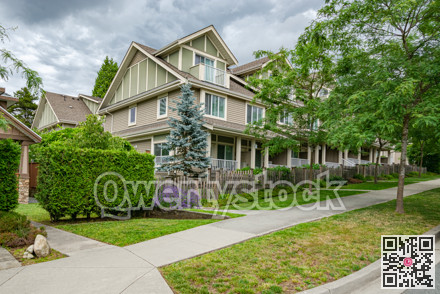 Row of townhouses with concrete pathway in front on couldy day in Vancouver, BC