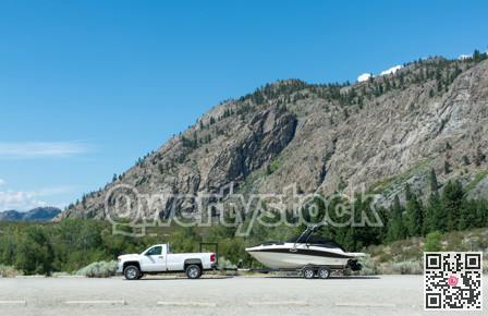 Summer landscape with white truck towing a boat to the water by gravel road