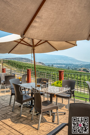 Street cafe tables under satin umbrellas with Okanagan valley overview