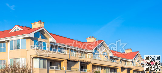 Residential building with red roofs on blue sky background.