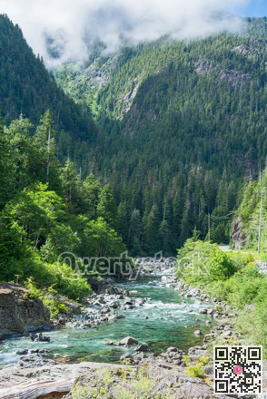 Mountain landscape with asphalt road and shallow river running through